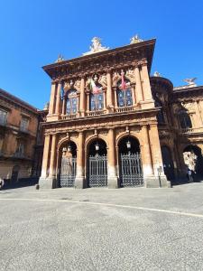 a large building with a gate with flags on it at Casta Diva Holiday Rooms in Catania