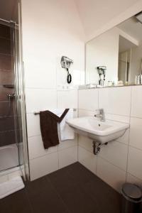 a white bathroom with a sink and a shower at Althoff´s Landhotel in Ochtrup