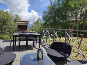 a deck with a table and chairs and a grill at Les Myrtilles, appartement au pied des pistes in Saint-Pierre-dels-Forcats