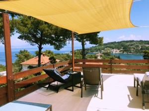 eine Terrasse mit Stühlen, einem Tisch und einem gelben Sonnenschirm in der Unterkunft Villa Zdena in Rogač