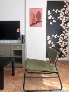 a room with a chair and a desk with a television at Le 20 Les Terrasses. Maison de bord de Loire in Chalonnes-sur-Loire