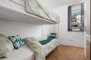 ein weißes Schlafzimmer mit einem Etagenbett und einem Fenster in der Unterkunft Apartment KATI&ANA in Rijeka