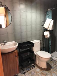 Un baño con inodoro, lavabo y espejo. en Pension Gabino (rooms), en El Ganso