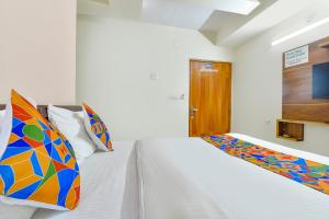 a white bedroom with a bed and a wooden door at FabHotel Vishwa in Ahmedabad