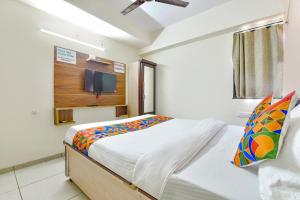 1 dormitorio con 1 cama y TV en la pared en FabHotel Vishwa en Ahmedabad
