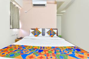 FabHotel Vishwa في أحمد آباد: غرفة نوم مع سرير ولحاف ملون