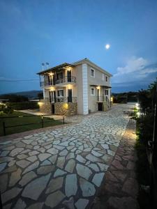 a large white house with a stone driveway at Tasos Cozy House in Lefkada