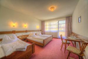 a hotel room with two beds and a desk at Burgenländerhof Hotel Garni in Mörbisch am See