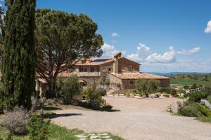 una grande casa in pietra con un albero e un vialetto di Dimora Santa Margherita - Relais di Charme a Cinigiano