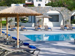 eine Gruppe von Stühlen und Sonnenschirmen neben einem Pool in der Unterkunft Coriva Beach Hotel & Bungalows in Koutsounári