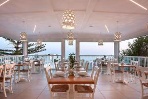 ein Esszimmer mit Tischen, Stühlen und Fenstern in der Unterkunft Coriva Beach Hotel & Bungalows in Koutsounári