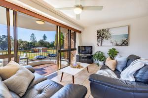 a living room with a couch and a tv at Coastal SOL -Right on Clarkes Beach! in Byron Bay