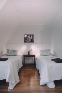 um quarto com duas camas com lençóis brancos e uma mesa em Vääksyn Apteekinmajoitus em Vääksy
