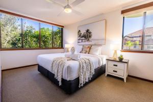 a bedroom with a large bed and large windows at Coastal SOL -Right on Clarkes Beach! in Byron Bay