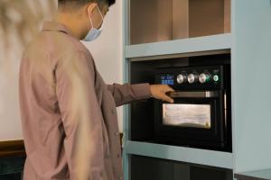 Um homem de máscara está a abrir um forno. em 秀川居 Xiuchuanju em Sanxia