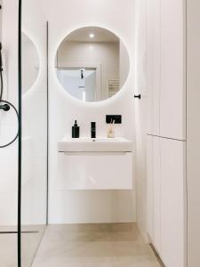 La salle de bains blanche est pourvue d'un lavabo et d'un miroir. dans l'établissement Miło Apartament Wakacyjna - pet friendly & free parking Mielno, à Mielno