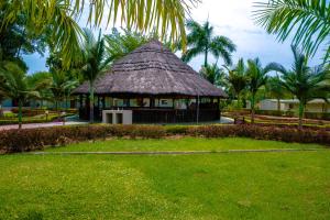 a hut with a grass roof in a park with palm trees at Grand Hotel Juba in Juba