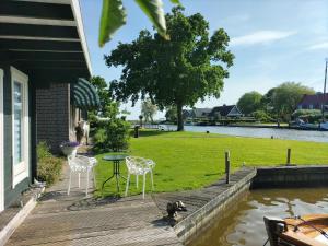 a deck with a table and chairs and a dog on it at Havenkantoortje in Woudsend