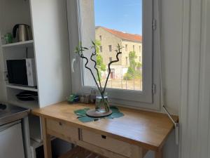 eine Vase auf einem Tisch vor einem Fenster in der Unterkunft Cosy Paris in Vitry-sur-Seine