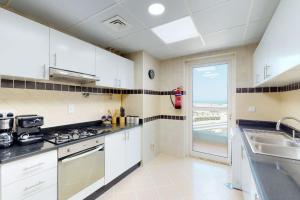 a kitchen with white cabinets and a view of the ocean at The Zen Tower - Vacationer in Dubai