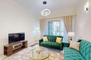 a living room with a green couch and a tv at The Zen Tower - Vacationer in Dubai