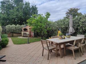 einen Tisch mit Stühlen und einem Sonnenschirm auf einer Terrasse in der Unterkunft VILLA FOR RYDER CUP in Guidonia