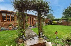 un giardino con pergolato di fronte a una casa di Clematis cabin a Hereford