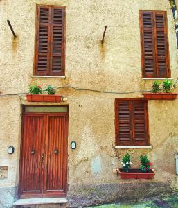 um edifício com uma porta e duas janelas e vasos de plantas em Casa Cavour em Norma