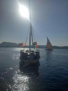 two boats floating on a body of water with the sun at Sailing boat in Aswan
