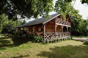 a log cabin with a black roof on a grass field at Dom pod Lipami in Bachórz