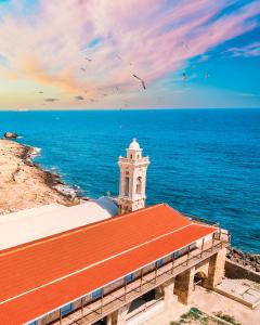 a building with a red roof next to the ocean at Paradise Karpaz Hotel & Restaurant in Rizokarpaso +32 photos