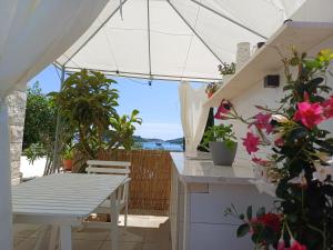 un patio con tavolo bianco, sedie e fiori di Apartments Grbin a Korčula