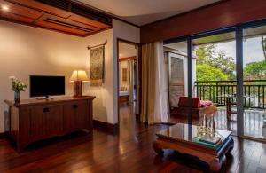 a living room with a television and a balcony at La Résidence Phou Vao, A Belmond Hotel, Luang Prabang in Luang Prabang