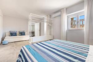 a white bedroom with a bed and two windows at Villa Amoenitas by Perle di Puglia in Ugento
