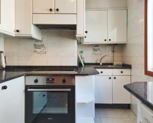 a kitchen with white cabinets and an oven at Desconectaengalicia El Pescador, vistas al puerto, 200m playa in Portonovo