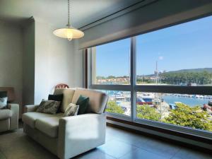 a living room with a couch and a large window at Desconectaengalicia El Pescador, vistas al puerto, 200m playa in Portonovo