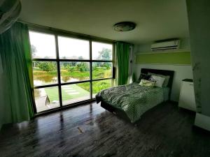 a bedroom with a bed and a large window at Summer Cottage Apartel in Bangkok