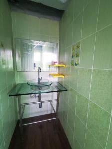 a green tiled bathroom with a sink and a mirror at Summer Cottage Apartel in Bangkok