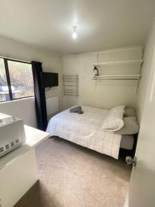 Habitación pequeña con cama y ventana en Small Wallet-Friendly Private Room in a 7 BR Shared House - The Ben's Room 6 en Queenstown
