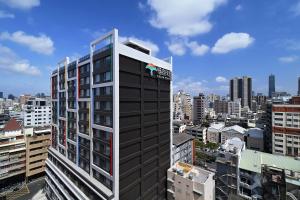 a tall building with a logo on it in a city at Fullon Poshtel - Kaohsiung in Kaohsiung