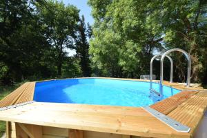 a pool with a wooden deck and a blue swimming pool at Adorable maison d'hôtes avec piscine- tiny house in Saubrigues