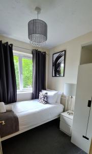 a bedroom with a bed with a window and a chandelier at Dreals Apartments in Stevenage