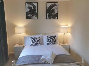 a bedroom with a white bed with two lamps at Dreals Apartments in Stevenage