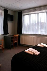 a hotel room with a bed and a desk and windows at Royal in Deventer