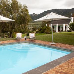 a swimming pool with two chairs and an umbrella at Ayama Manor House in Wellington