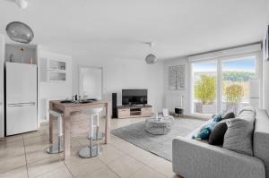 a white living room with a couch and a kitchen at La Marquette - Appartement avec balcon in Toulouse