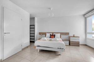 a white bedroom with a bed and a window at La Marquette - Appartement avec balcon in Toulouse