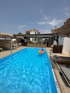 a person laying on a raft in a swimming pool at koukounari 3 superior rooms in Skala