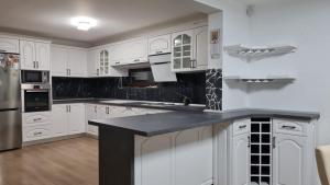 a kitchen with white cabinets and a black counter top at Casa Diana&Ovi in Câmpulung Moldovenesc