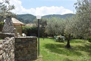 un giardino con tavolo, parete in pietra e lampada di CHALET TRA GLI ULIVI: • giardino • WiFi • A/C • bbq a Capri Leone